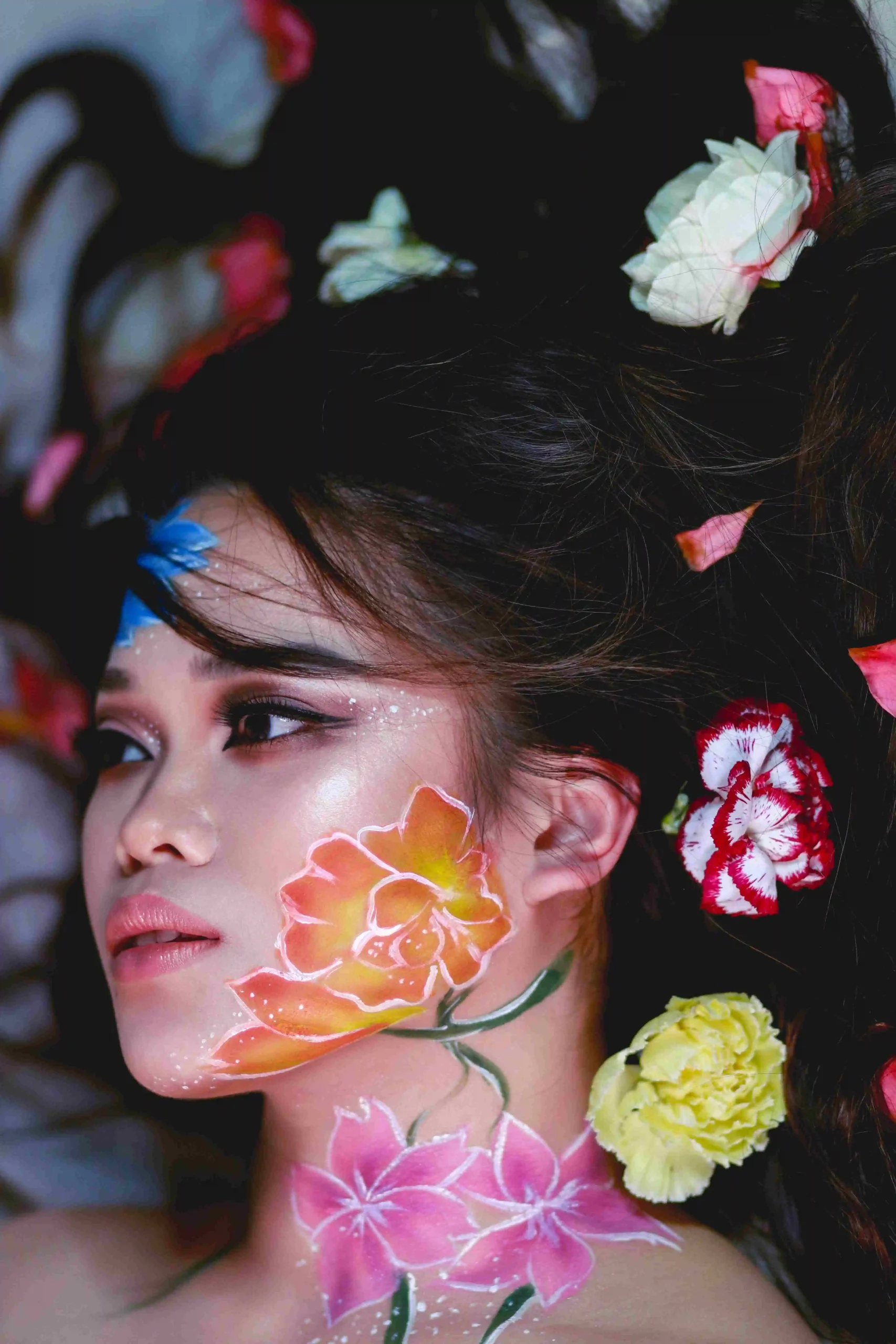 Woman with floral body art and flowers in hair for beauty editorial