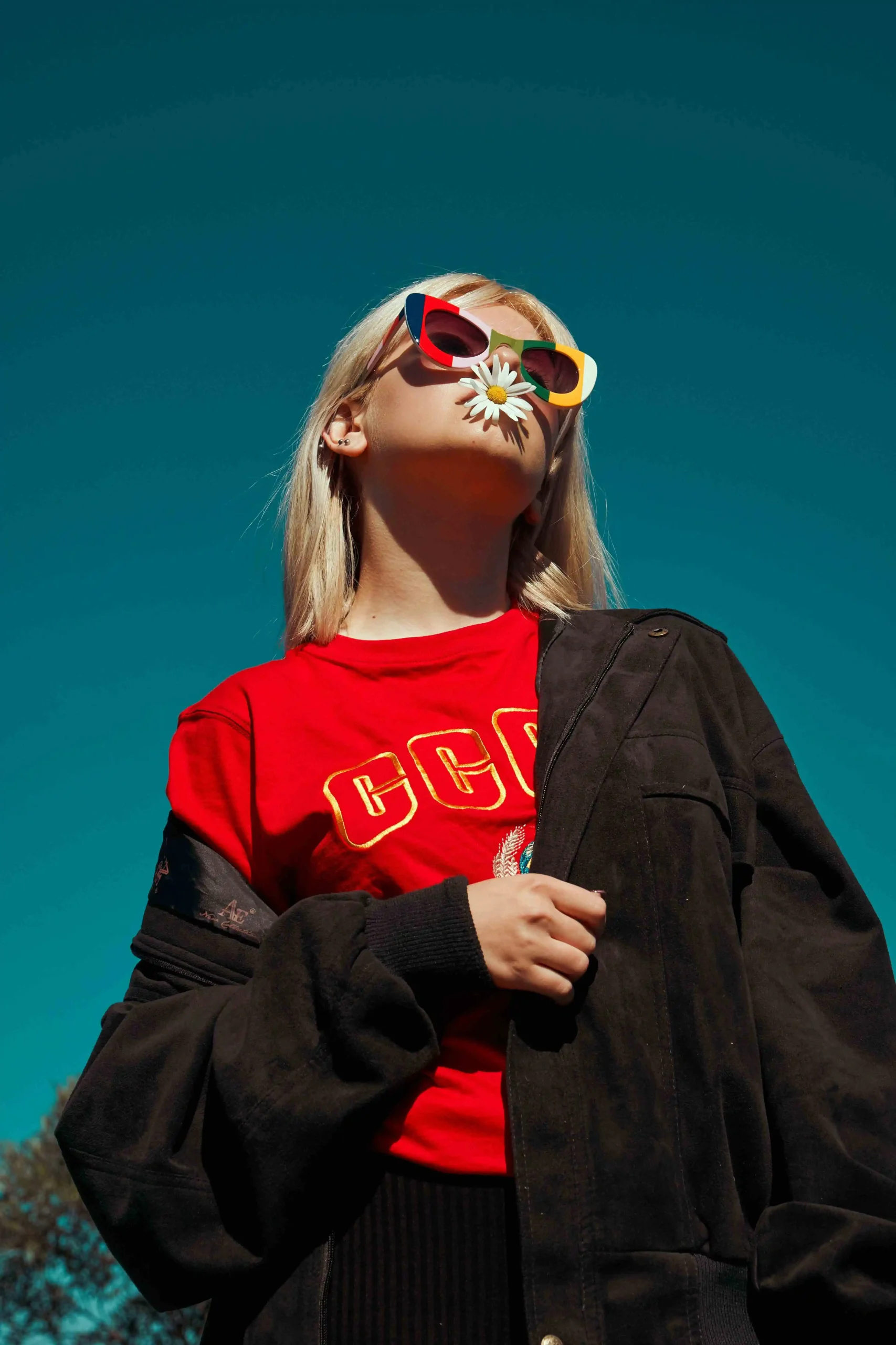 Fashion editorial portrait with colorful sunglasses against blue sky