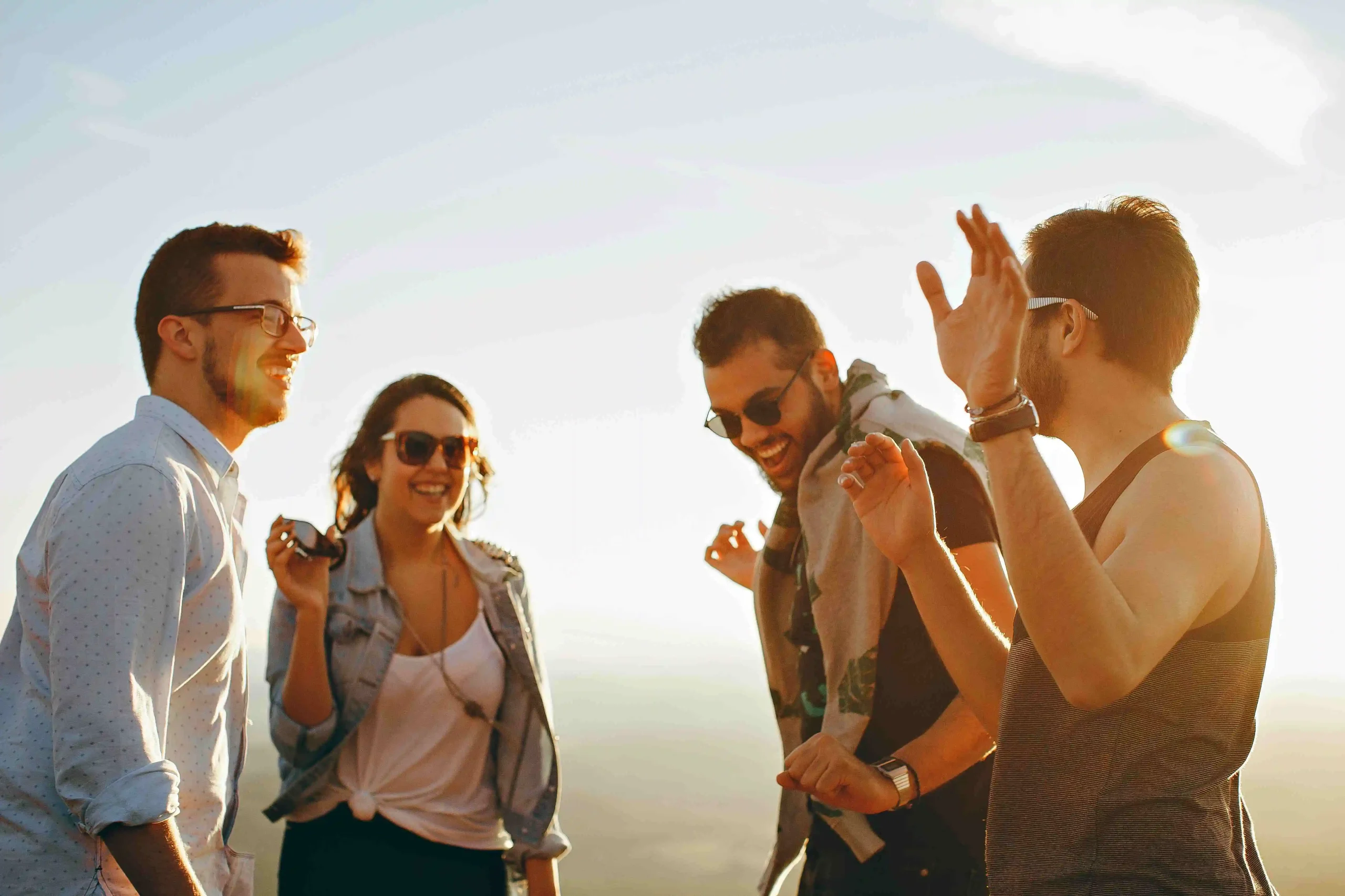 Group of friends laughing outdoors at sunset for lifestyle editorial